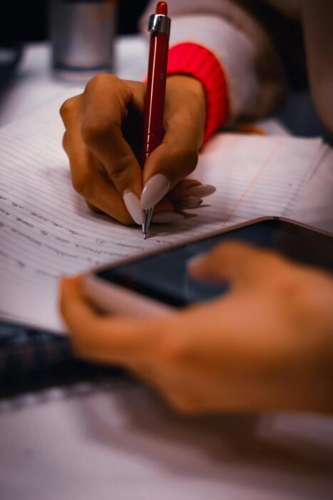 pessoa com telemóvel na mão e a escrever