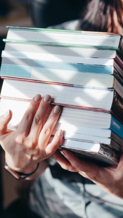 pilha de livros nas m&atilde;os de uma pessoa