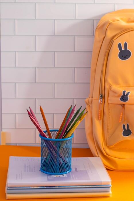 cesto de l&aacute;pis em cima de pilha de livros e mochila