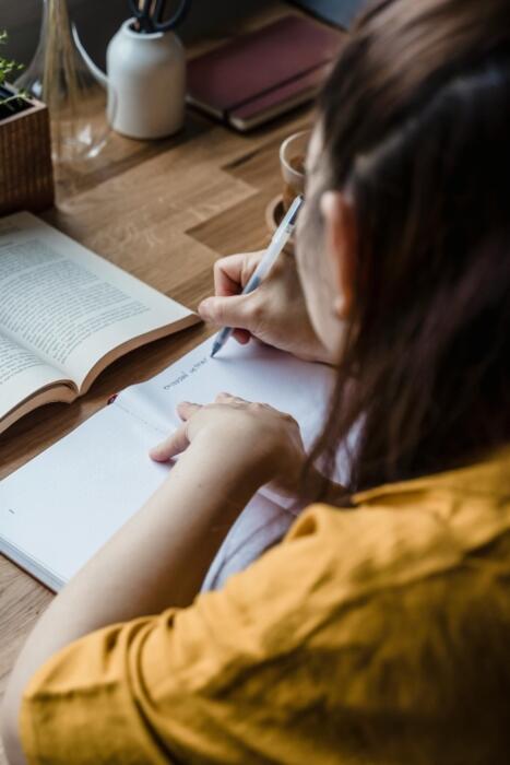 rapariga a estudar com livro e caderno